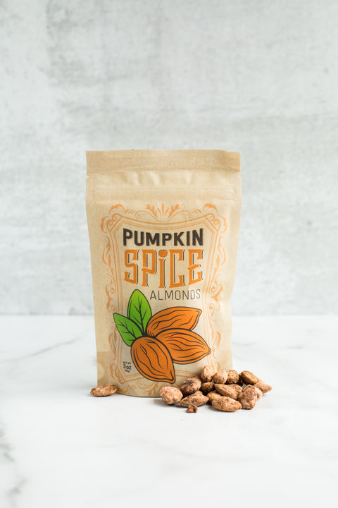 Bag of pumpkin spice almonds with scattered nuts, showcasing vegan, dairy-free fall snack featuring cinnamon, nutmeg, and ginger.