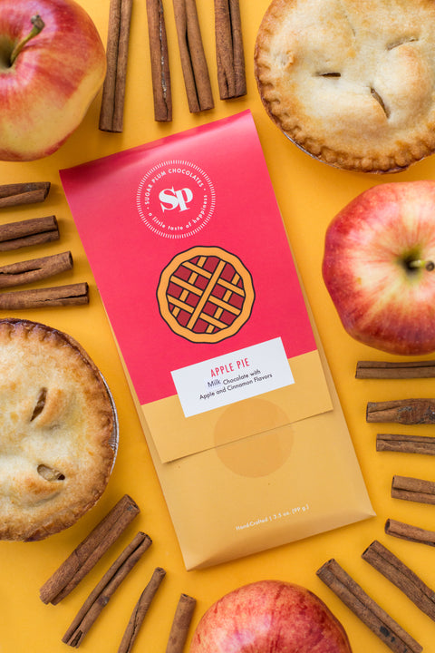 Nostalgic apple pie chocolate bar surrounded by apples, pies, and cinnamon sticks on a yellow background.