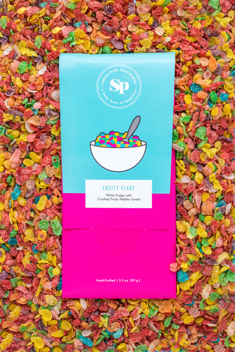 Fruity Flake chocolate bar with colorful cereal design, nestled in a bed of crushed, multicolored fruity pebbles.