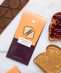 Nostalgic Peanut Butter & Jelly Chocolate Bar with bread slices topped with peanut butter and jelly, displayed on a marble surface.