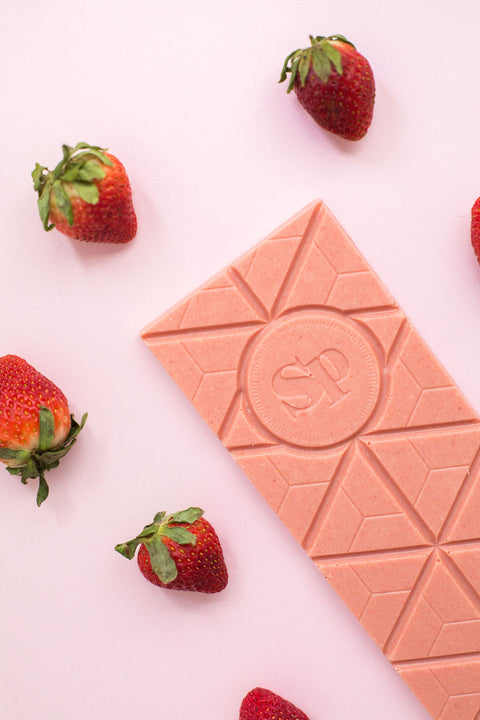 Strawberry Cheesecake White Chocolate Bar with fresh strawberries on a pink background.