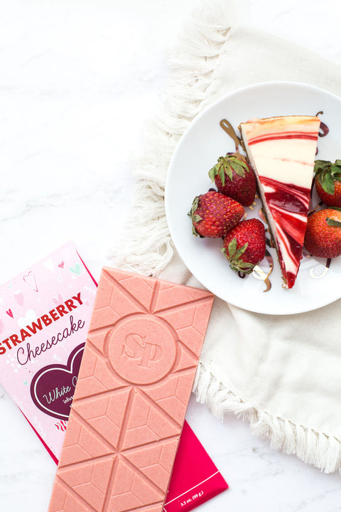 Strawberry Cheesecake White Chocolate Bar with Fresh Strawberries and Slice of Cheesecake on a Plate