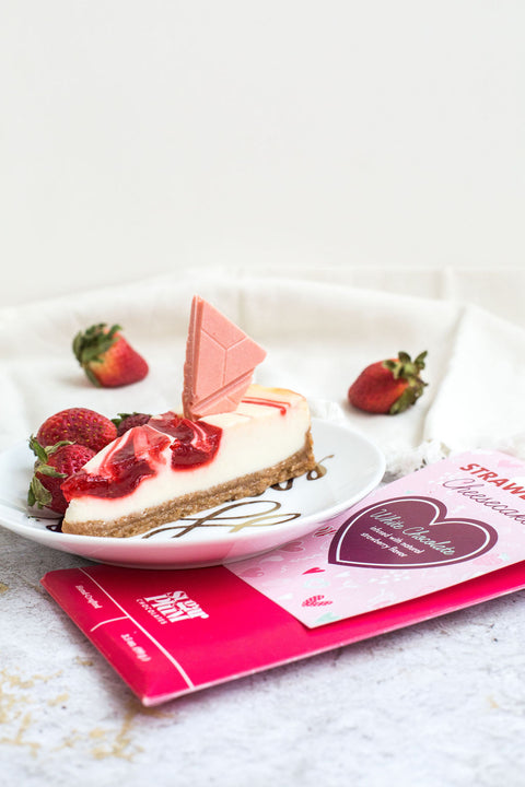 Strawberry cheesecake white chocolate bar with fresh strawberries on a plate, perfect gourmet dessert for gifting and indulging.