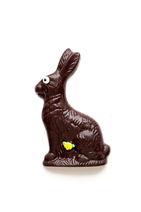 Handmade dark chocolate Easter bunny with decorative eye and flower, wrapped in a cello bag with a bow, perfect for holiday baskets.