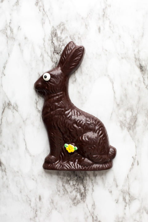 Handmade Dark Chocolate Easter Bunny with spring flower detail and eye on marble background.