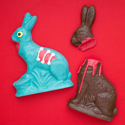 Handcrafted chocolate zombie bunny and victim set, limited edition Halloween or Easter candy gift, on a red background.