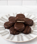 Chocolate-covered sandwich cookies arranged on a plate, showcasing rich, dark chocolate and a creamy filling inside.