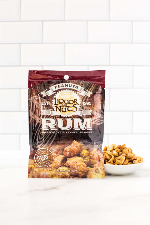 Rum flavored gourmet peanuts in a bag, part of a liquor-inspired snack collection, with a bowl of peanuts on a white surface.
