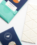 Cinnamon Roll White Chocolate Bars packaging and white chocolate square, showcasing graham cracker and sticky bun flavors.