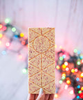 Hand holding a Candy Cane White Chocolate Bar with festive lights in the background, showcasing holiday-themed packaging.