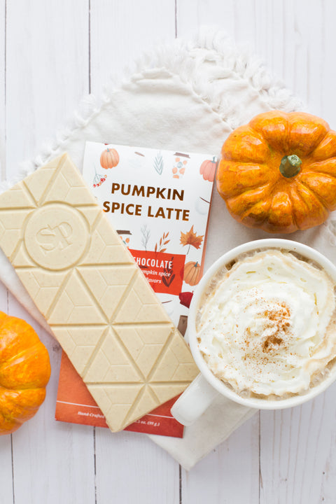 Pumpkin Spice Latte chocolate bar with white chocolate, surrounded by fall pumpkins and a whipped cream-topped latte.