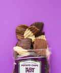 Pack of chocolate-covered potato chips against a purple background, showcasing milk and dark chocolate flavors by Sugar Plum Chocolates.