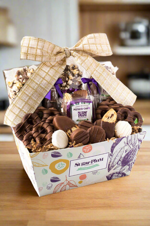 Gourmet chocolate gift basket with 25 handcrafted treats by Sugar Plum, featuring milk, dark, and white chocolate snacks, adorned with a bow.