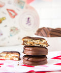 Milk chocolate-covered peanut butter cracker cookies stacked on a heart-patterned cloth with heart-shaped box in the background.