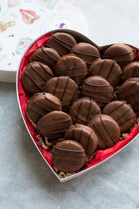 Heart-shaped box of handcrafted milk chocolate-covered peanut butter cracker cookies, perfect sweet and salty treat.