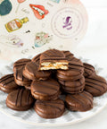 Milk chocolate-covered peanut butter cracker cookies stacked on a plate in front of a decorative heart-shaped box.