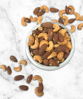 Premium salted cashews and almonds in a white bowl on a marble surface, showcasing Damn Man Black Label's refined nut selection.