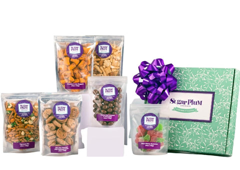 Gift box of assorted snacks with purple bow and labeled pouches, including nuts, chocolates, and gummies from Sugar Plum.