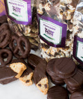 Assortment of handcrafted dark chocolate snacks including pretzels, cookies, and popcorn from Sugar Plum's gourmet gift box.