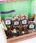 Gourmet chocolate assortment gift box with popcorn, chocolate-covered pretzels, and snacks in milk, dark, and white chocolate.