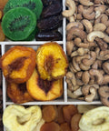 Gourmet dried fruit and nut tray with apricots, kiwis, dates, peaches, apples, cashews, and almonds on a wooden platter.