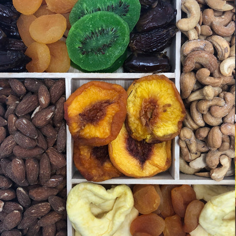 Gourmet dried fruit and nut tray with apricots, kiwis, cashews, and almonds on a wooden platter, perfect healthy snack gift.