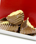 Chocolate-covered potato chips on a white plate with a red background, showcasing a sweet and salty snack blend.
