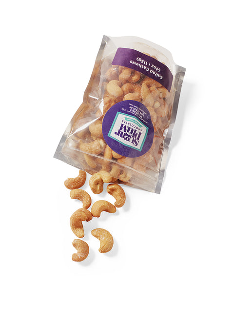 "Bag of salted cashews spilling out, part of The Comfort Box gourmet snacks care package"