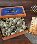 Kosher for Passover Pareve Dairy-Free Truffles in gift tin with matzah and menorah on wooden table.
