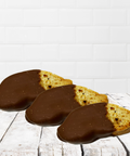 Three chocolate-dipped biscotti on a rustic wooden table, part of a thoughtful get-well-soon gift box for comfort and recovery.