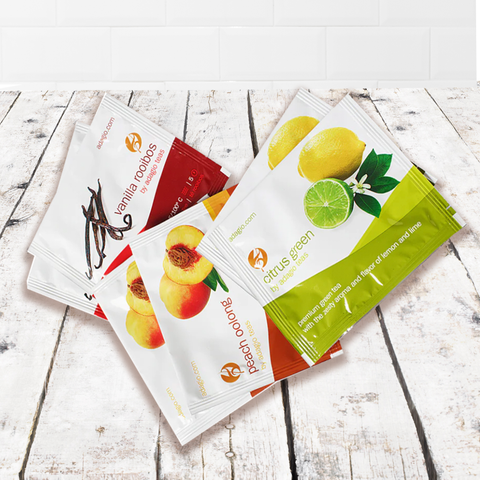 Assorted tea packets including citrus green, peach oolong, and vanilla rooibos on a rustic wooden surface.