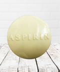 Soap shaped like an aspirin tablet on a rustic wooden surface