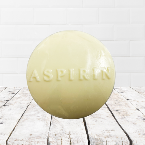 Soap shaped like an aspirin tablet on a rustic wooden surface