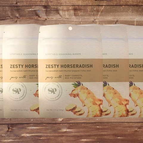 Five packs of Zesty Horseradish Vegetable Seasoning on a wooden background.