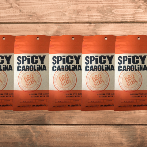 Five packs of Spicy Carolina BBQ Seasoning on a wooden surface