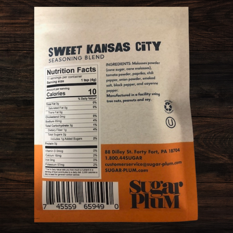 Sweet Kansas City BBQ seasoning blend package with nutrition facts and ingredients by Sugar Plum on a wooden surface.