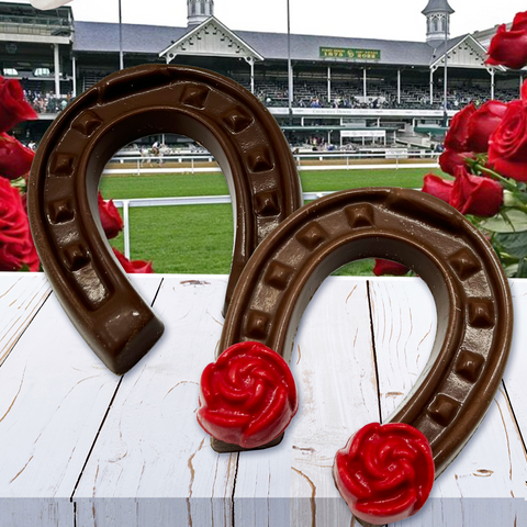Chocolate horseshoe with red rose, Kentucky Derby theme, on white wooden table in front of racecourse backdrop with roses.