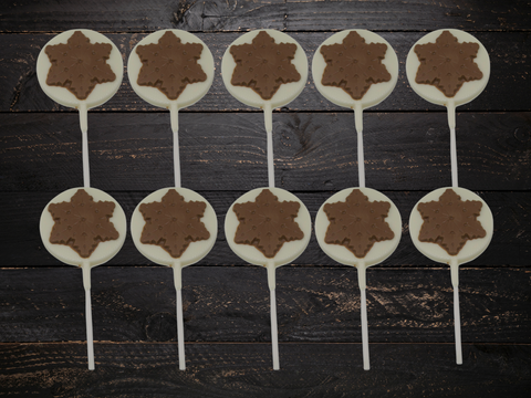 Festive milk and white chocolate snowflake lollipops set on a rustic wooden table, perfect for Christmas gifting and stocking stuffers.