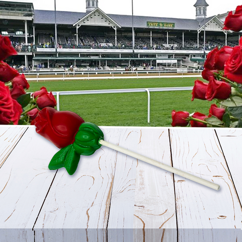 Red rose lollipop on a table with a Kentucky Derby racetrack in the background.