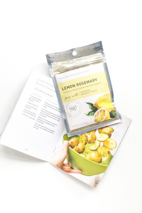 Lemon Rosemary Vegetable Seasoning blend packet with cookbook and roasted potatoes.