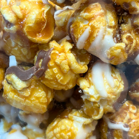 Gourmet caramel corn drizzled with white and milk chocolate, showcasing a sweet and crunchy handcrafted snack.