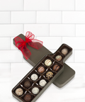 Wine truffle box assortment with 12 handcrafted chocolate truffles in a wine bottle-shaped box, adorned with a red ribbon.